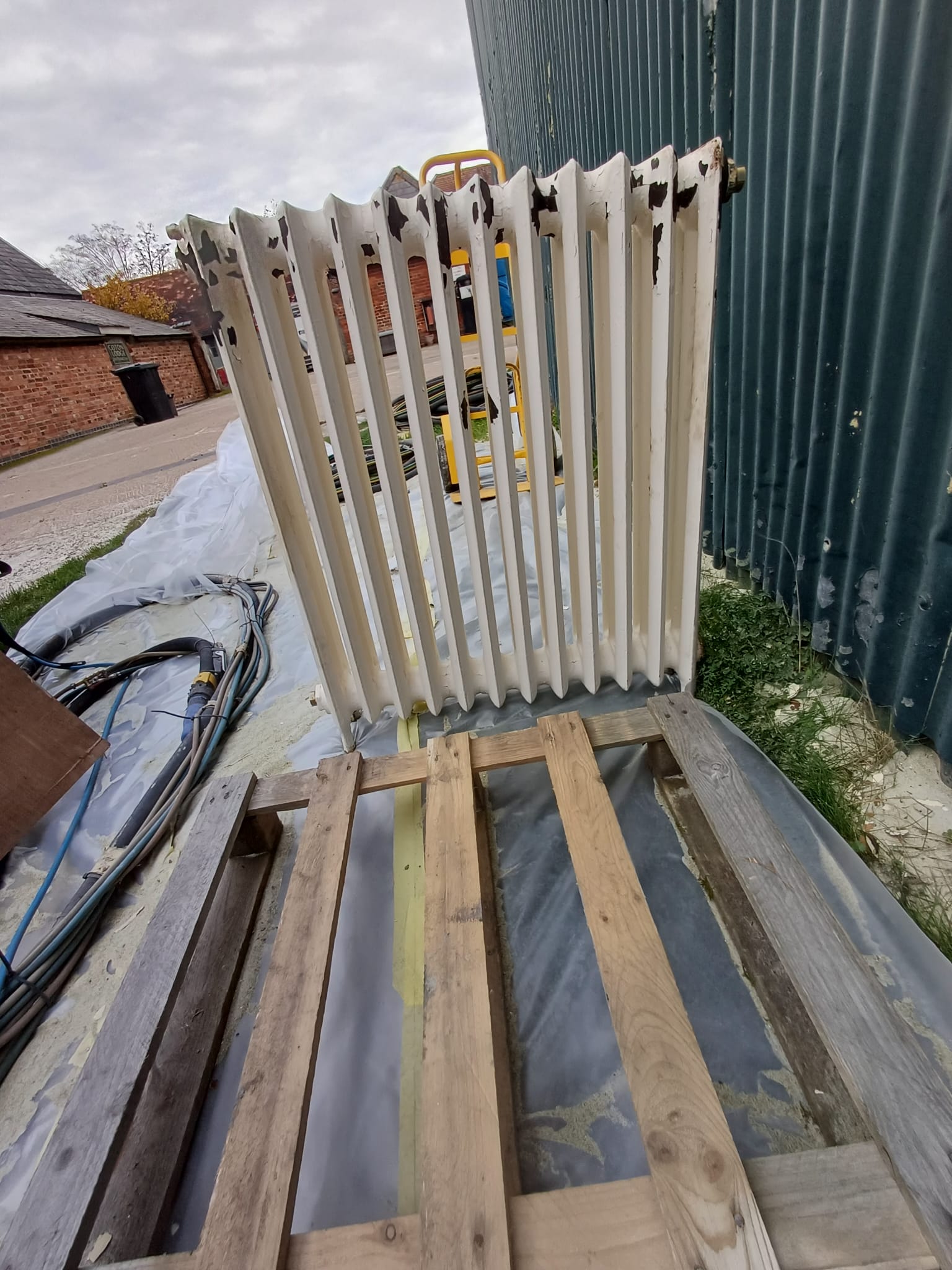 Cast iron radiator showing multiple coating layers and surface rust